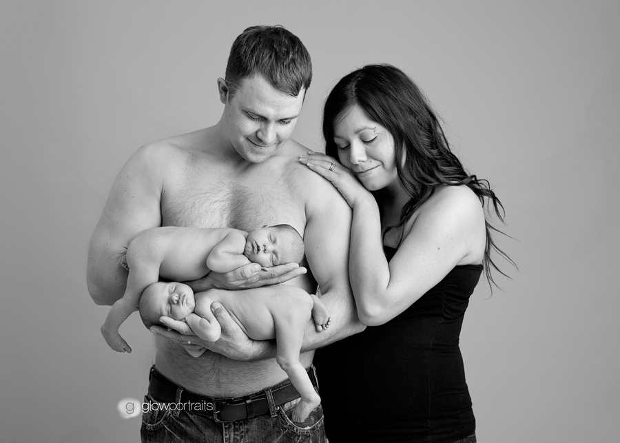 mom and dad posing with twin newborns