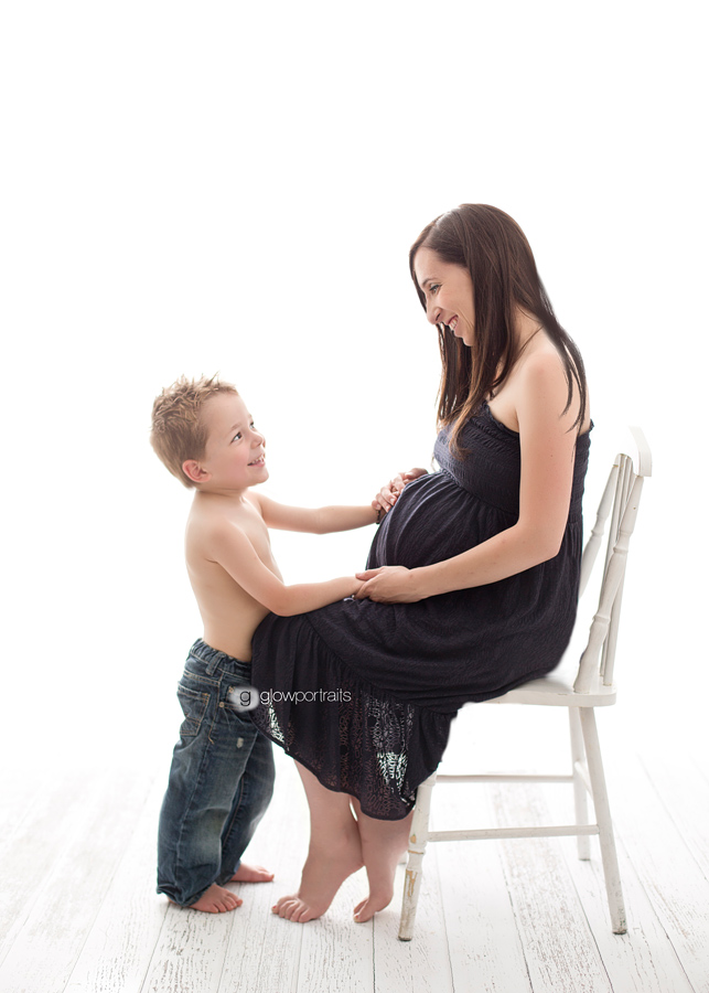 mom sitting on chair with son touching belly