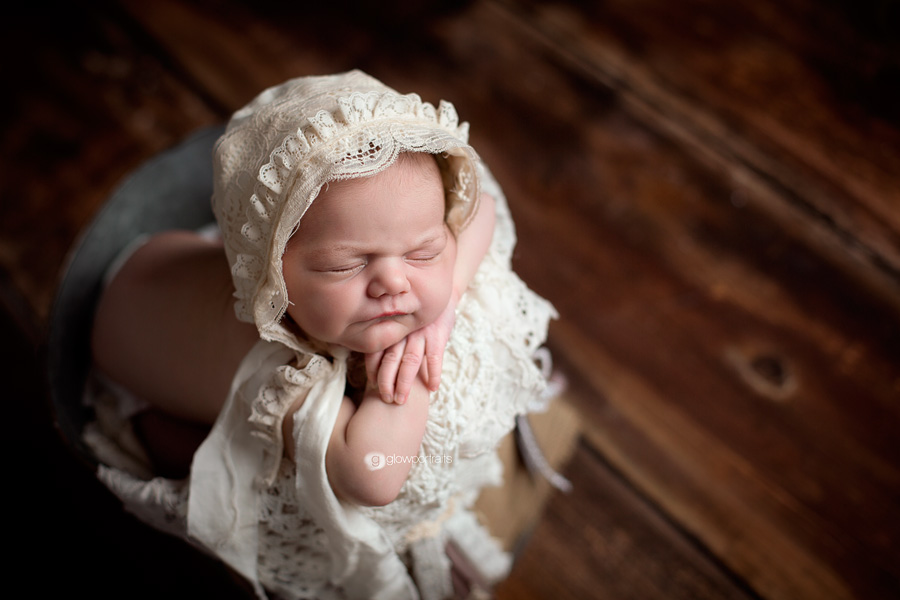 newborn girl in metal bucket with lace bonnet