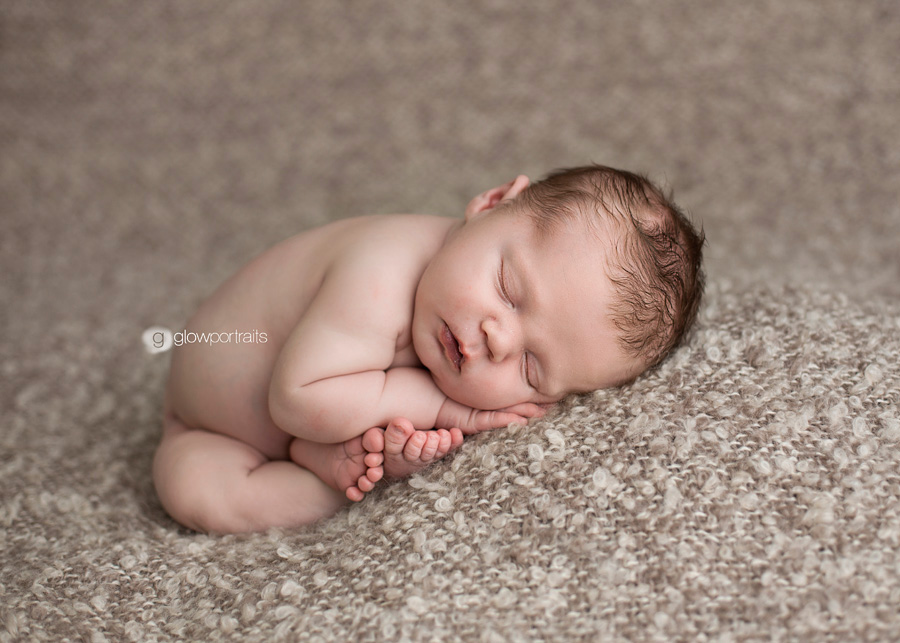 newborn baby by in taco pose on beanbag