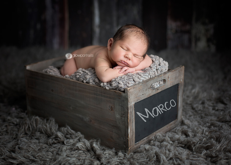 newborn lying in wooden box with name on it in chalk