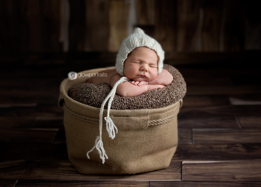 newborn baby in basket with white hat on