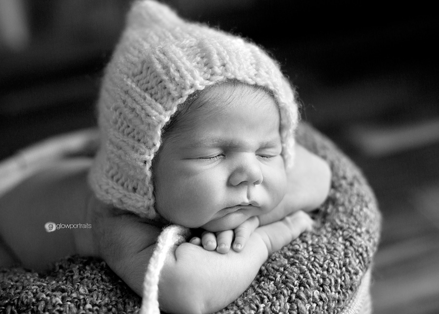 newborn in bucket wearing bonnet