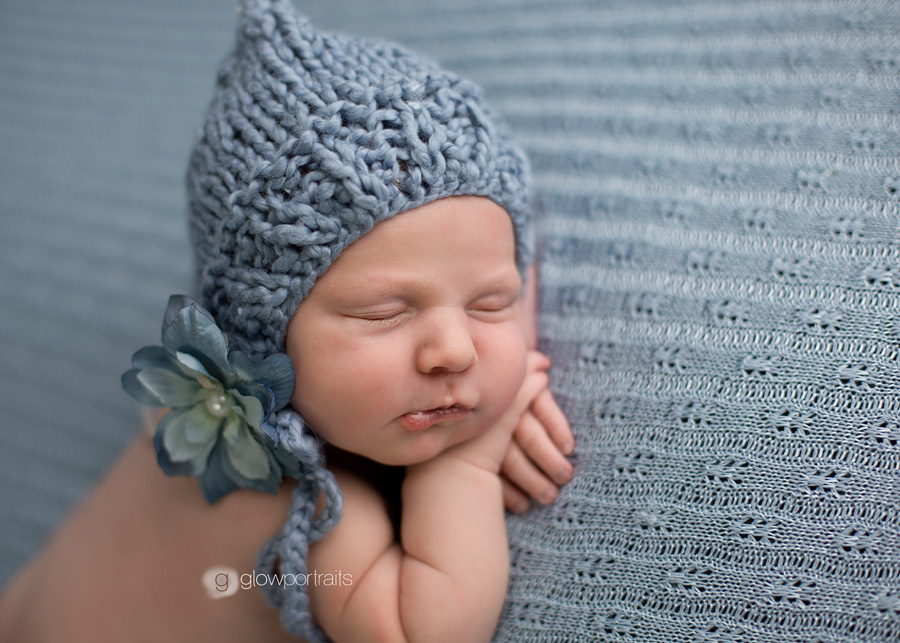 newborn girl in blue bonnet with flower