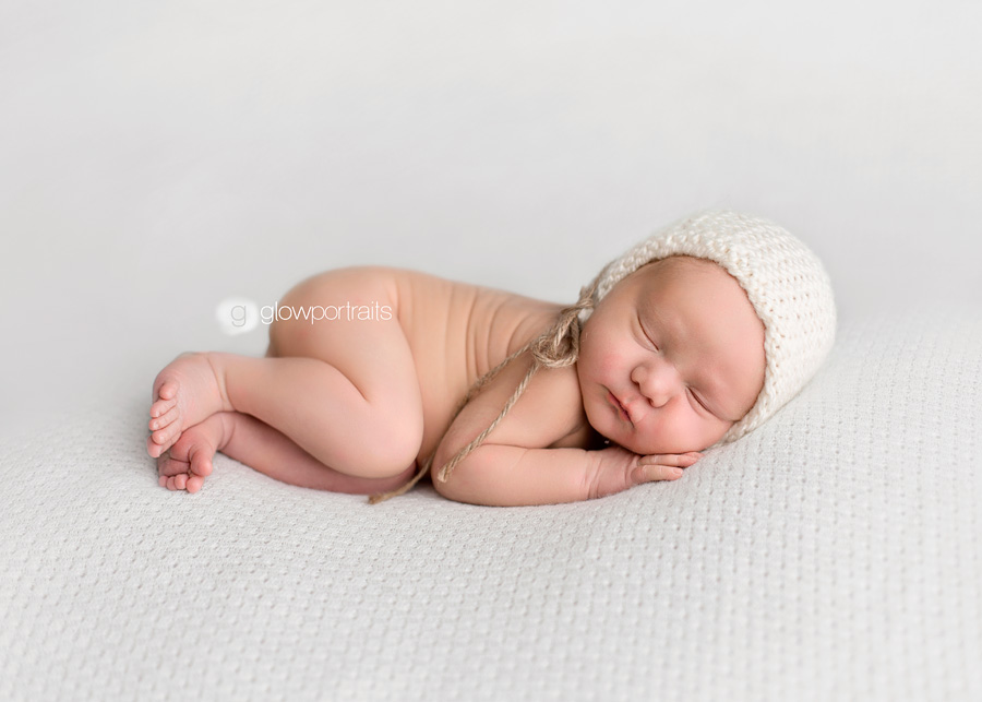 baby boy wearing white bonnet on beanbag