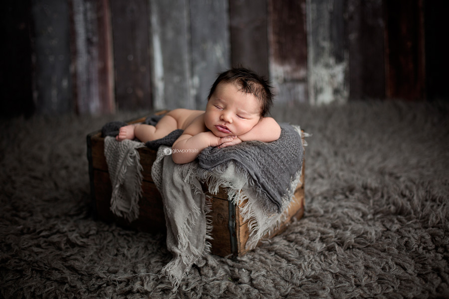 newborn baby in box with blankets on fur rug 