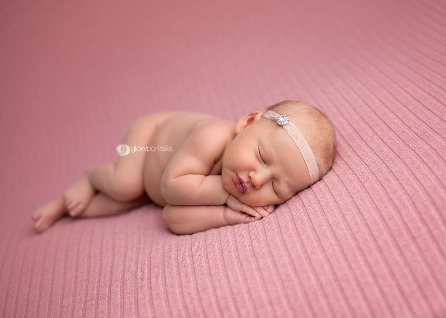 newborn lying on side on pink blanket