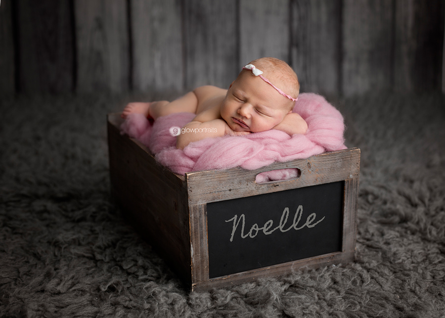 newborn baby girl on pink fluff in box