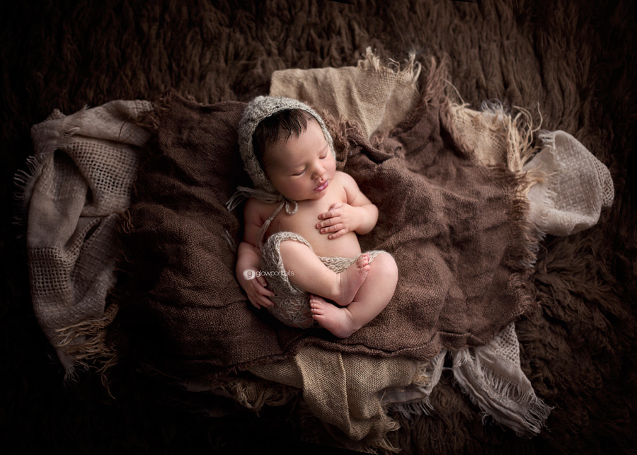 newborn in hat and pants on brown flokati fur rug