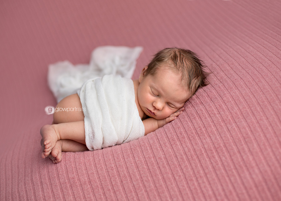 baby girl on pink beanbag fabric with white wrap