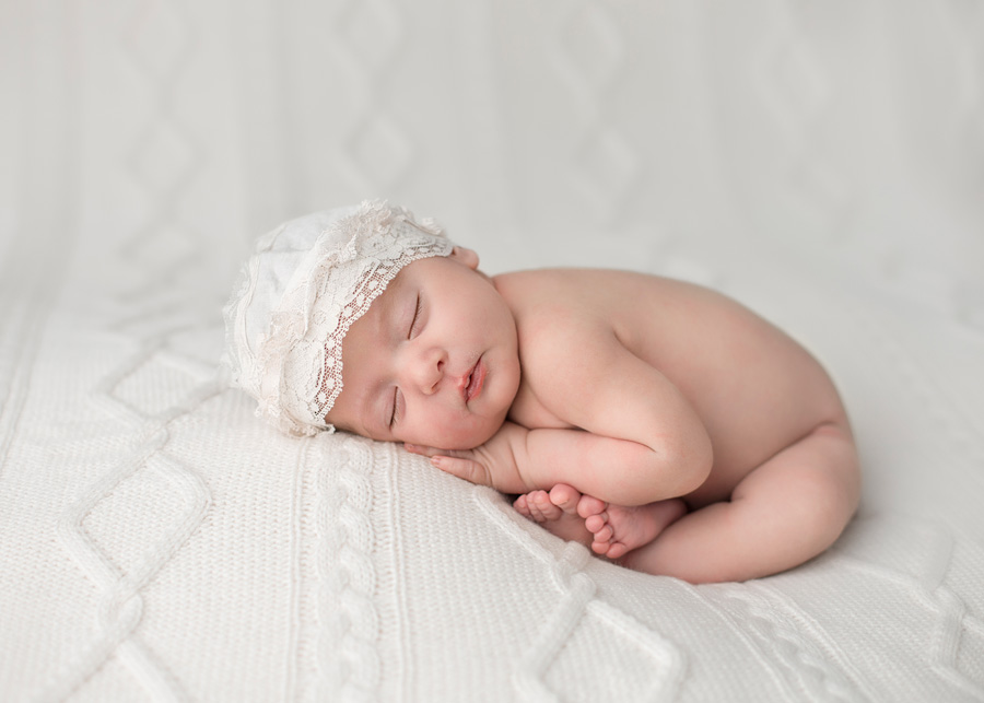 newborn baby girl on white blanket in taco pose