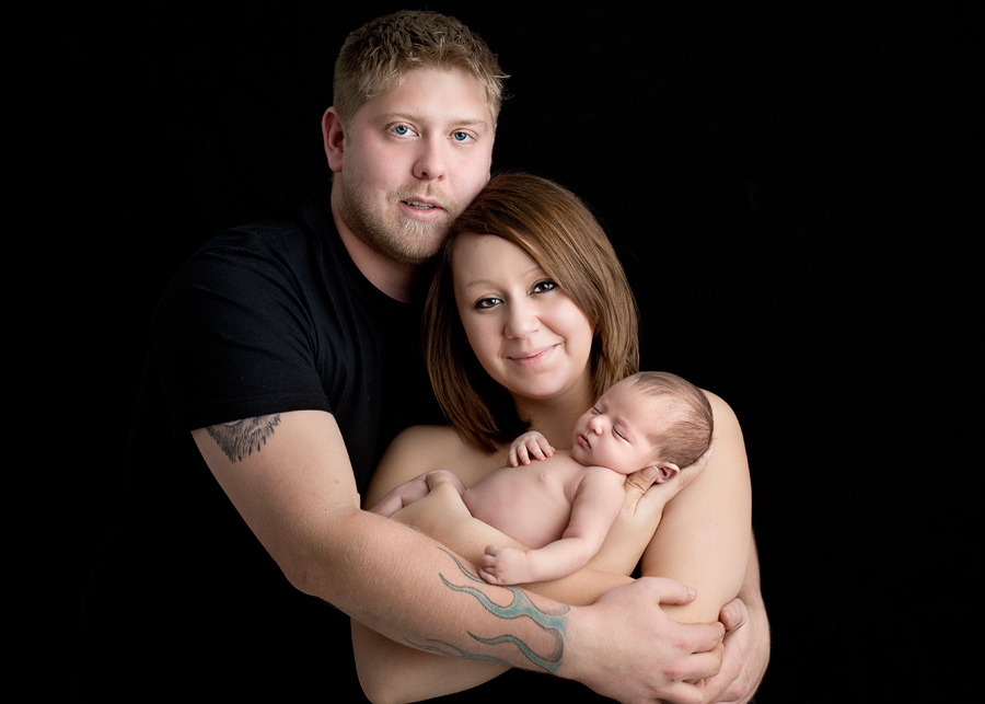 parents cuddling newborn baby