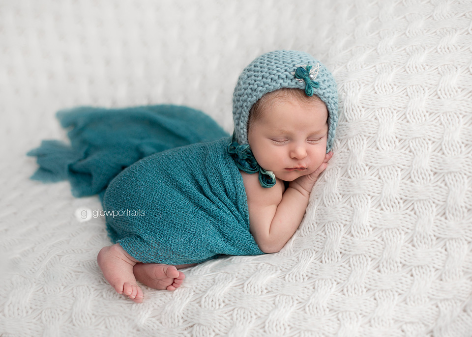 newborn wrapped in teal fabric on beanbag