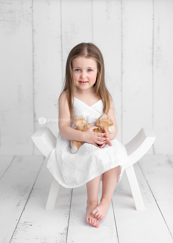 adorable girl in white dress sitting on white chair