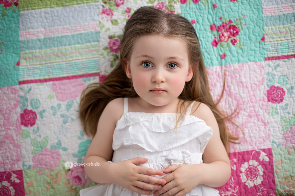 beautiful little girl lying on colourful quilt