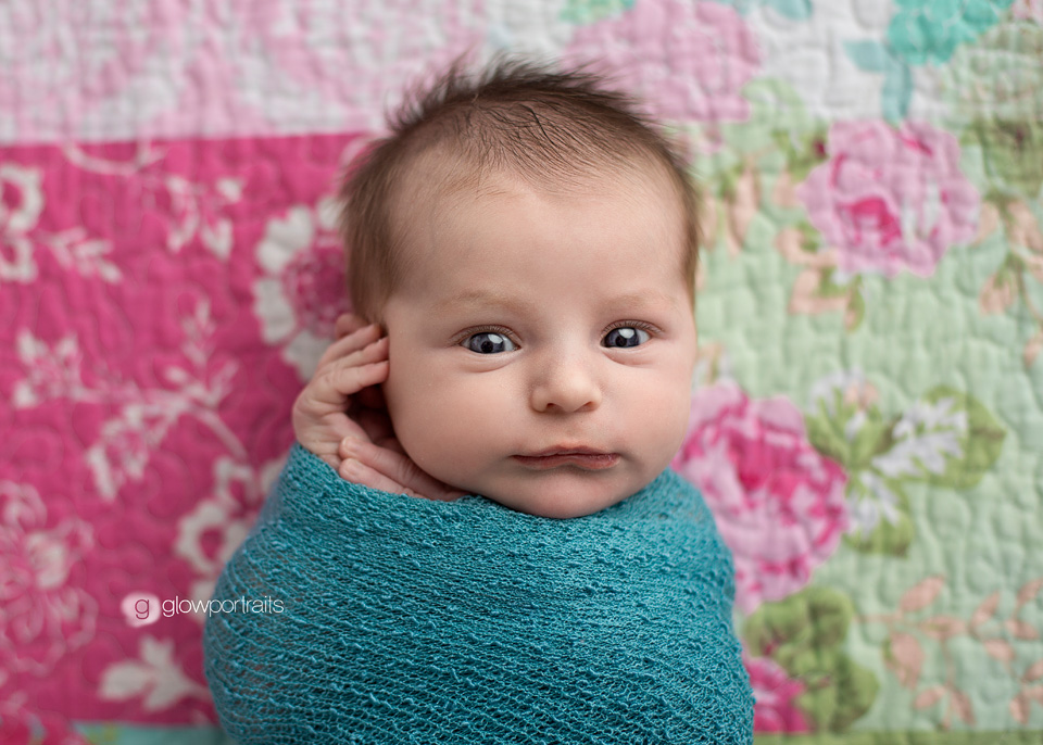 awake wrapped newborn on quilt
