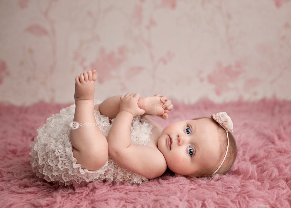 baby wearing lace romper grabbing toes