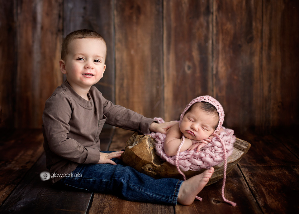 brother touching his newborn sister 