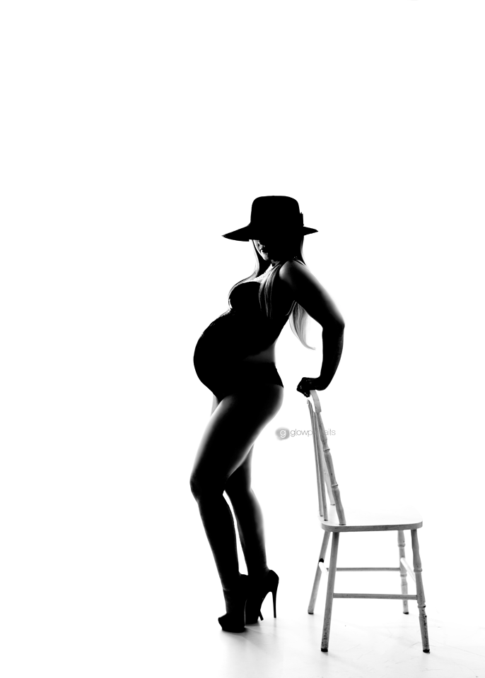 black and white silhouette of pregnant lady holding chair wearing high heels