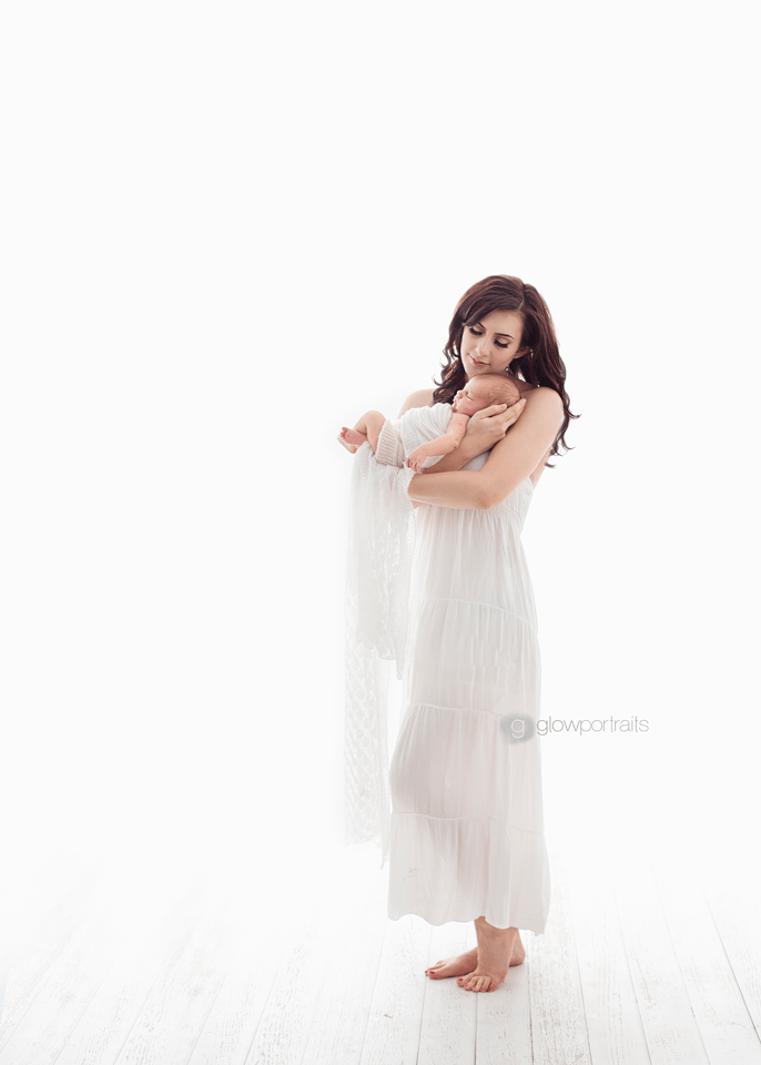 mom snuggling baby wearing white dress
