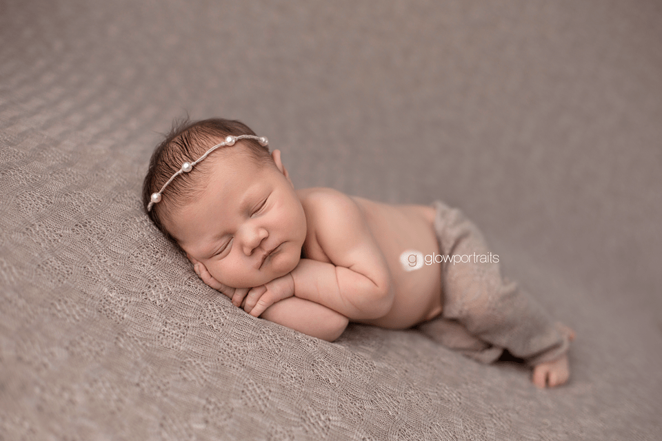 newborn girl snuggled wearing beige pants