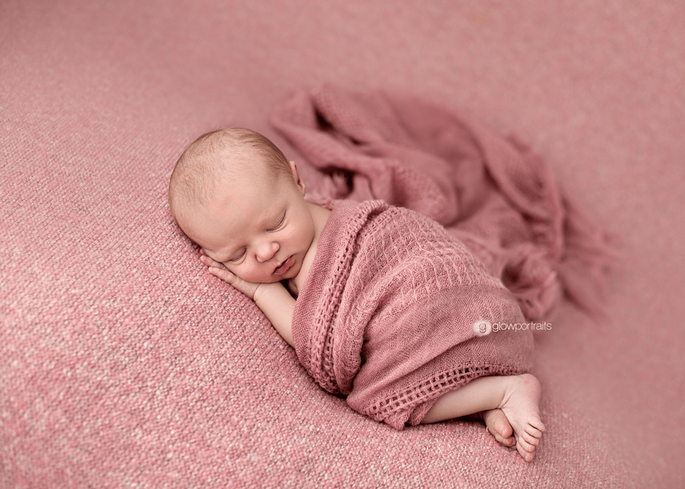 newborn girl wrapped in pink fabric