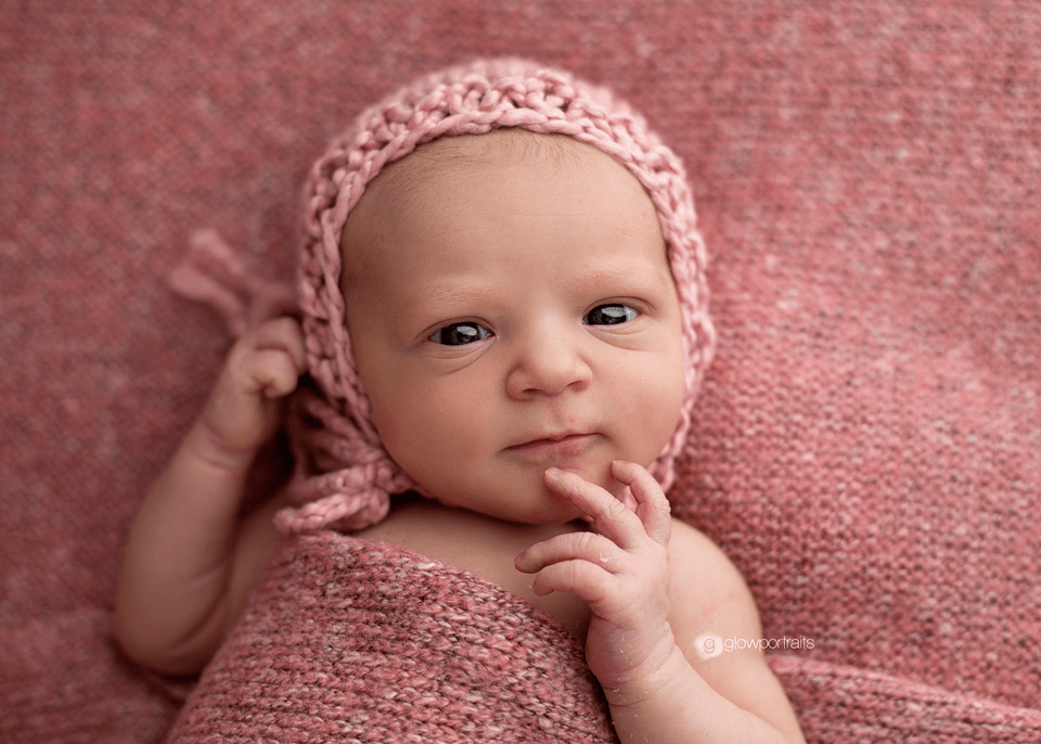 awake newborn wearing pink hat